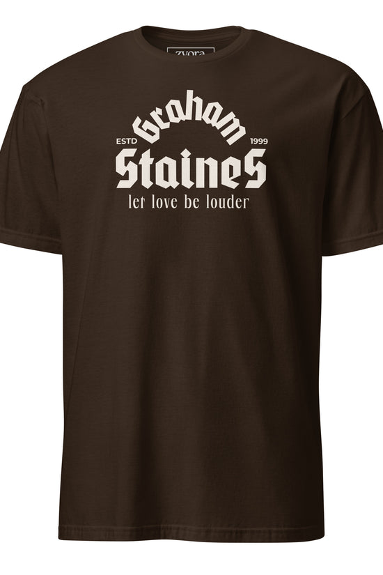 “Graham Staines – Let Love Be Louder” Christian Dark Chocolate graphic tee, inspired by 1 Corinthians 13:13. Faith-based gift, scripture-inspired apparel for men and women.